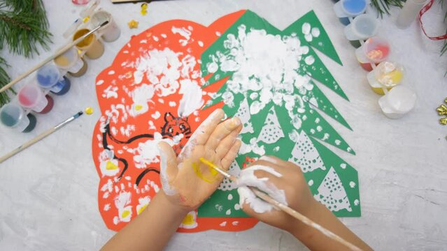 Child making a greeting card  Craft for children. Nice greeting card with a Christmas snowy forest. . Top view
