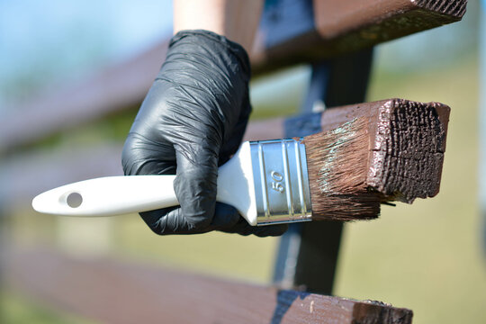 Painting wood base with brush and wood paint in gloves