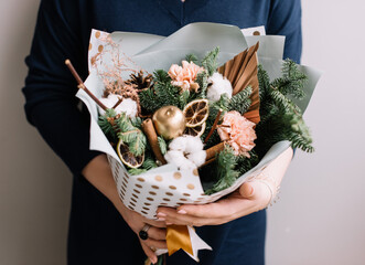 Very nice young woman holding big and beautiful winter bouquet of fresh carnations, cotton, pine cones, nobilis spruce , cropped photo, bouquet close up
