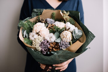 Very nice young woman holding big and beautiful winter bouquet of fresh Nobilis spruce, pine cones, carnations, cotton, cropped photo, bouquet close up - 538087031