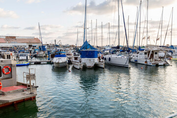 Fototapeta na wymiar Sailing yachts and fishing boats in the marina in the evening. Romantic rest and business.