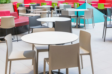 Empty tables in the cafe at the food court in the mall. Place for meetings and entertainment.