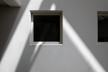 window with rays of light on a white wall and shadows