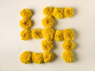 Swastika - a Hindu religious symbol made with fresh and bright golden yellow Marigold flowers. Hindu wedding or religious background and graphics.