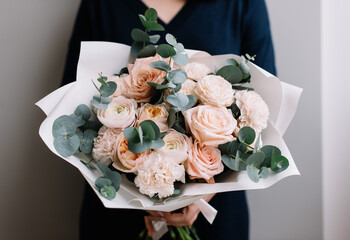 Very nice young woman holding big and beautiful bouquet of fresh roses, carnations, eucalyptus flowers in pastel pink colors, cropped photo, bouquet close up - 538087094