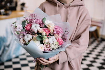 Very nice young woman holding big and beautiful bouquet of fresh carnations, cotton, roses,...