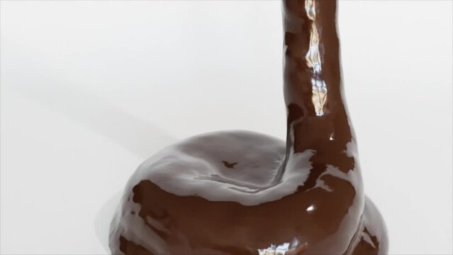 Liquid chocolate flows slowly onto a white surface