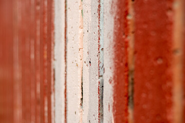 A close-up of a roughly painted wooden plank fence in soft focus.