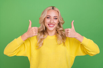 Photo of sweet young blond lady thumb up wear yellow sweater isolated on green color background