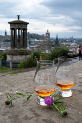 Two glasses of single malt scotch whisky and view from Calton hill to park and old parts of Edinburgh city in rainy day, Scotland, UK
