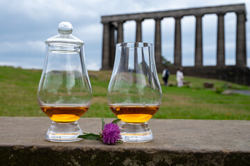 Two glasses of single malt scotch whisky and view from Calton hill to park and old parts of Edinburgh city in rainy day, Scotland, UK
