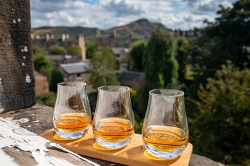 Flight of single malt scotch whisky served on old window sill in Scottisch house with view on old part of Edinburgh and hills, Scotland, UK