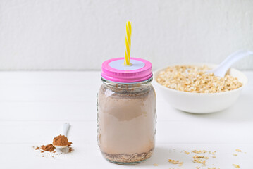 Morning healthy breakfast. Cocoa milk and oatmeal granules. Wooden white background.