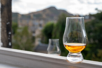 Glass of single malt scotch whisky served on old window sill in Scottisch house with view on old part of Edinburgh, Scotland, UK