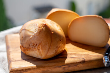Italian yellow smoked cheese scamorza served on olive tree wooden plank