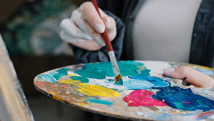 Closeup woman female hand artist painter paints draws creating new art work on canvas in workshop...