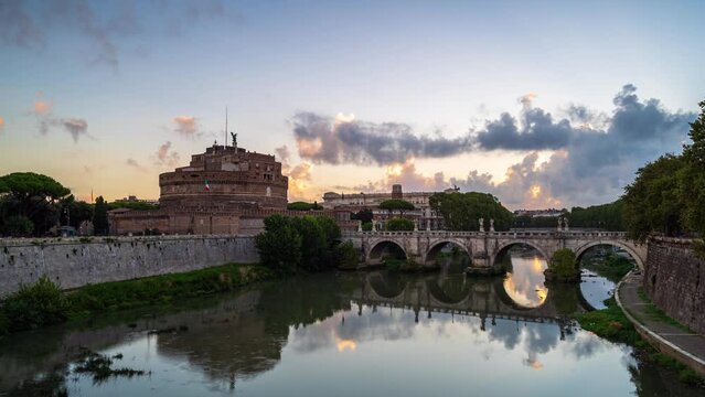 Time lapse video with moving clouds at sunrise above medieval St. Angelo castle and Vittorio Emanuele II Bridge over Tiber river in Rome, Italy