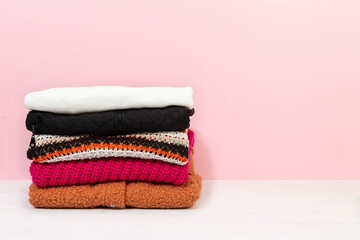 Obraz na płótnie Canvas sweaters stacked on pink ground