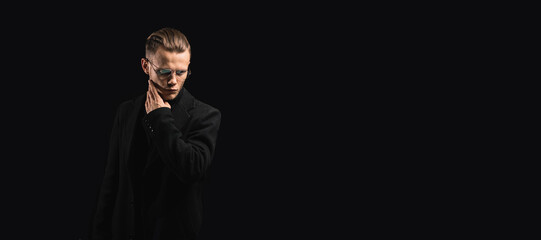brutal young man in glasses in a black coat on a dark background, hair styling by a handsome man.