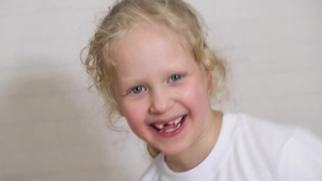 Close-up beautiful little girl 6-7 years old has lost milk teeth. Loss of milk teeth, replacement of permanent teeth and have fun 4k
