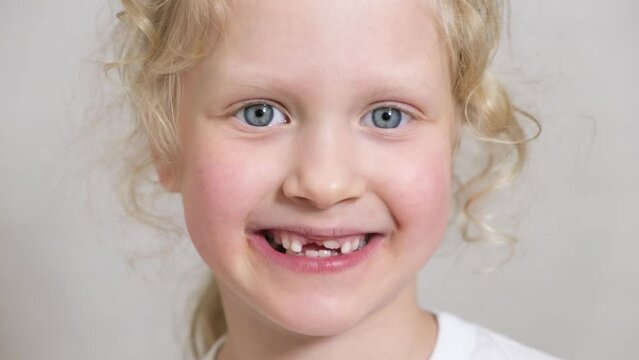 Close-up beautiful little girl 6-7 years old has lost milk teeth. Loss of milk teeth, replacement of permanent teeth and have fun 4k