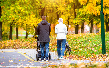 A married couple rolls a baby stroller in a city Park