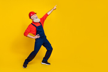 Full length photo of nice grandpa dance boogie woogie have fun point empty space dressed safety uniform isolated on yellow color background