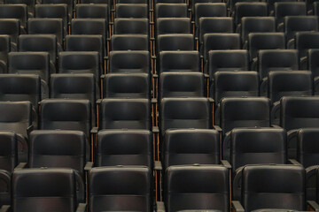 Theater auditorium with emphasis on the black chairs and wooden sides, all the same giving continuity and lines.