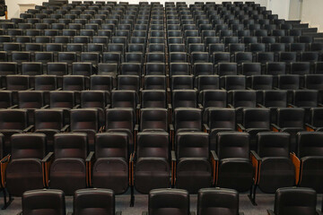 Theater auditorium with emphasis on the black chairs and wooden sides, all the same giving...