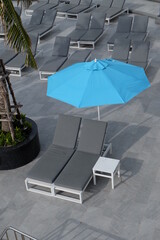 Blue umbrellas and gray sunbeds by the sea for tourists.