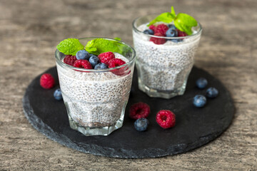 Healthy breakfast or morning with chia seeds vanilla pudding raspberry and blueberry berries on table background, vegetarian food, diet and health concept. Chia pudding with raspberry and blueberry