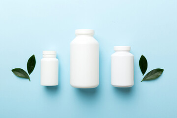 supplement pills with medicine bottle health care and medical top view. Vitamin tablets. Top view mockup bottle for pills and vitamins with green leaves, natural organic bio supplement, copy space