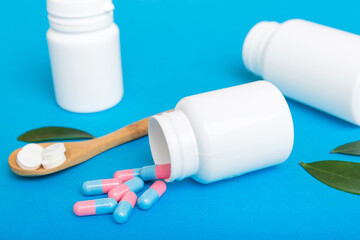different drugs and health supplement pills poured from a medicine bottle health care and medical top view on colored background