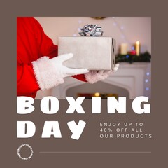 Composition of boxing day sales text over santa claus holding christmas present