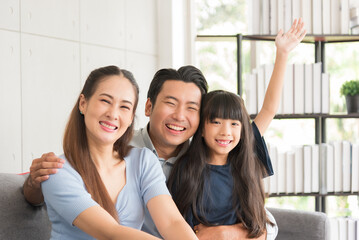 Portrait of happy mother father and daughter family sitting on couch together relaxing at home.
