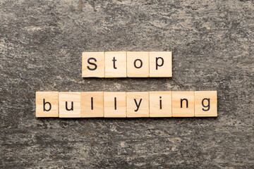 Fototapeta premium Stop Bullying word written on wood block. Stop Bullying text on cement table for your desing, concept