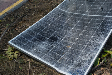 A broken solar panel, a torn panel mount lie on the ground. Consequences of a natural disaster. Green energy and natural conditions