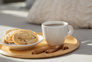 cup of coffee on wooden tray on bed in cozy bedroom