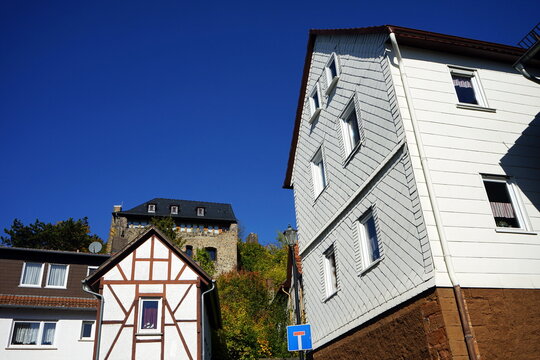 Sanierte alte Wohnh&auml;user mit Spitzgiebel, Fachwerk und Schindeln vor dem Burgmannenhaus vor blauem Himmel im Sonnenschein im Herbst in Staufenberg bei Lollar im Kreis Gie&szlig;en in Hessen