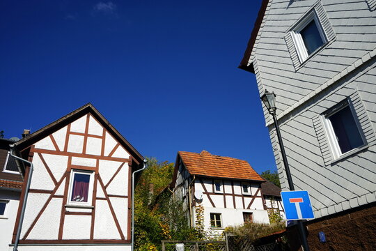 Restaurierte kleine Fachwerkh&auml;user mit Spitzgiebel und Fassade mit Schindeln vor blauem Himmel im Sonnenschein im Herbst in Staufenberg im Kreis Gie&szlig;en in Hessen