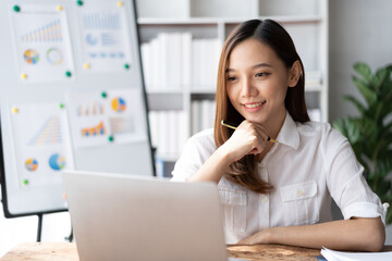 Portrait of an Asian young business Female working on a laptop computer in her workstation.Business people employee freelance online report marketing e-commerce telemarketing concept.