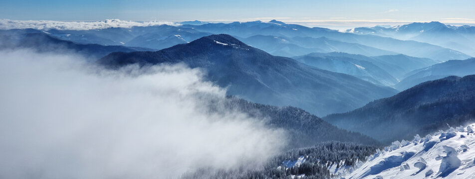 Beautiful sunny winter landscape in thу mountains. Mountain and fir trees covered with snow and clouds.