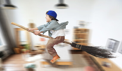 Happy boy is flying on a broomstick like a wizard. A child's fantasy. Childhood.