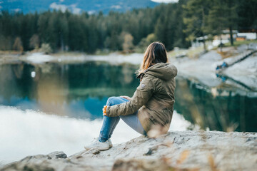 Woman sitting by a swiss mountain lake, Caumasee Graubünden, Switzerland