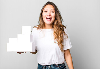 hispanic pretty woman looking happy and pleasantly surprised with white boxes packages