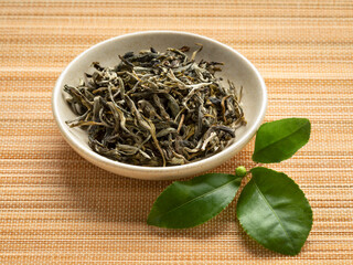 Dried white monkey tea leaves, Bai Mao Hou, close up in a bowl with fresh tea leaves in front