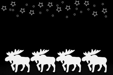 White wooden reindeer on a black background, top border with white stars, christmas silhouette. Top view, copy space.	