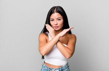 pretty latin woman looking annoyed and sick of your attitude, saying enough! hands crossed up...