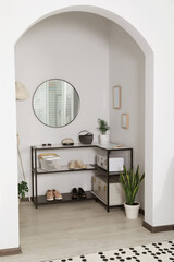 Hallway interior with stylish furniture and round mirror on light wall
