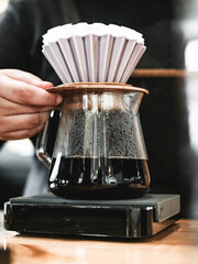 Barista holding a filter with coffee inside straining. Espresso coffee process. Using a coffee pod with coffee inside. Peaceful environment coffeshop working.